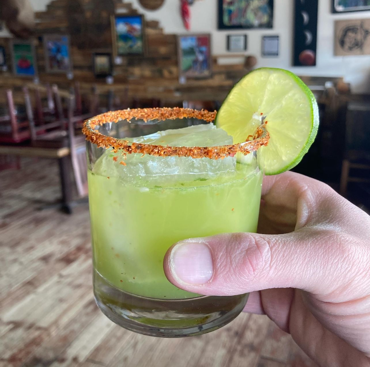 A chili-rimmed margarita with a lime wheel held up in the tasting room