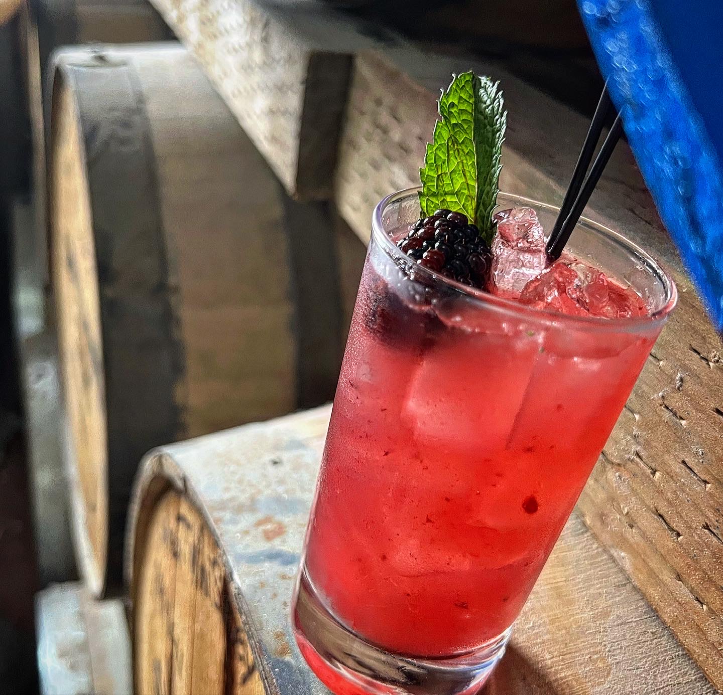 A blackberry mint smash over crushed ice on a whiskey barrel