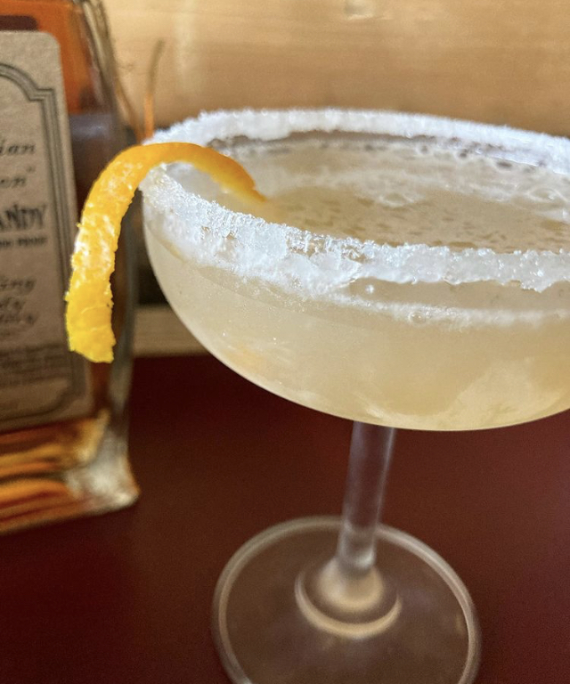 A sugar-rimmed brandy sidecar with an orange twist beside the Appalachian Temptation bottle