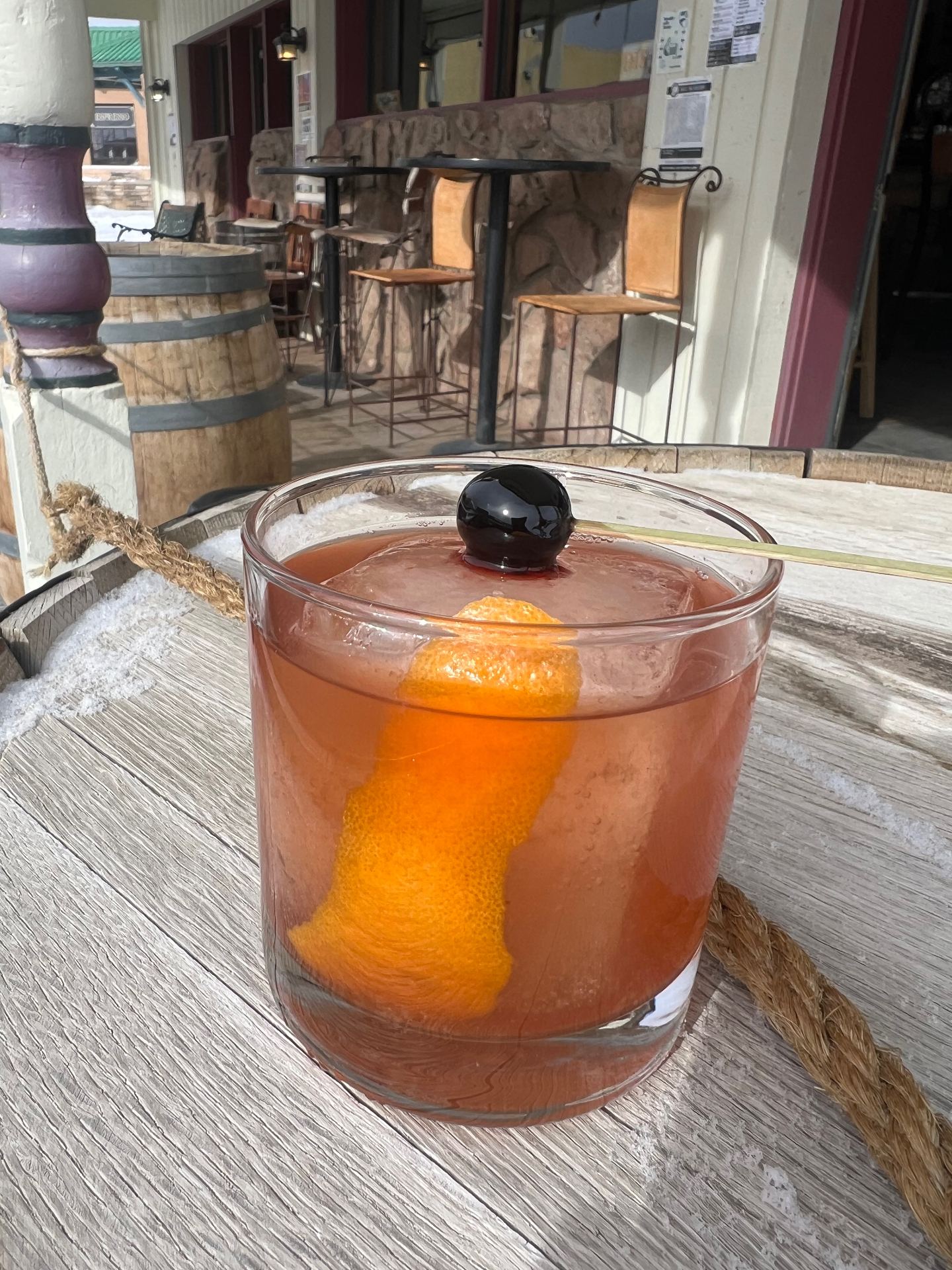 An old fashioned with a brandied cherry and orange peel on the snowy front porch