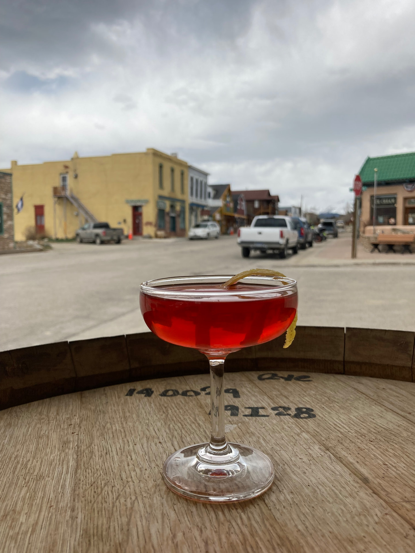 A ruby coupe with a lemon twist on a whiskey barrel overlooking Main Street