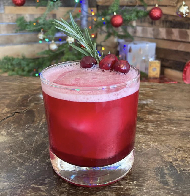 A cranberry sour with rosemary and fresh cranberries by the Christmas tree
