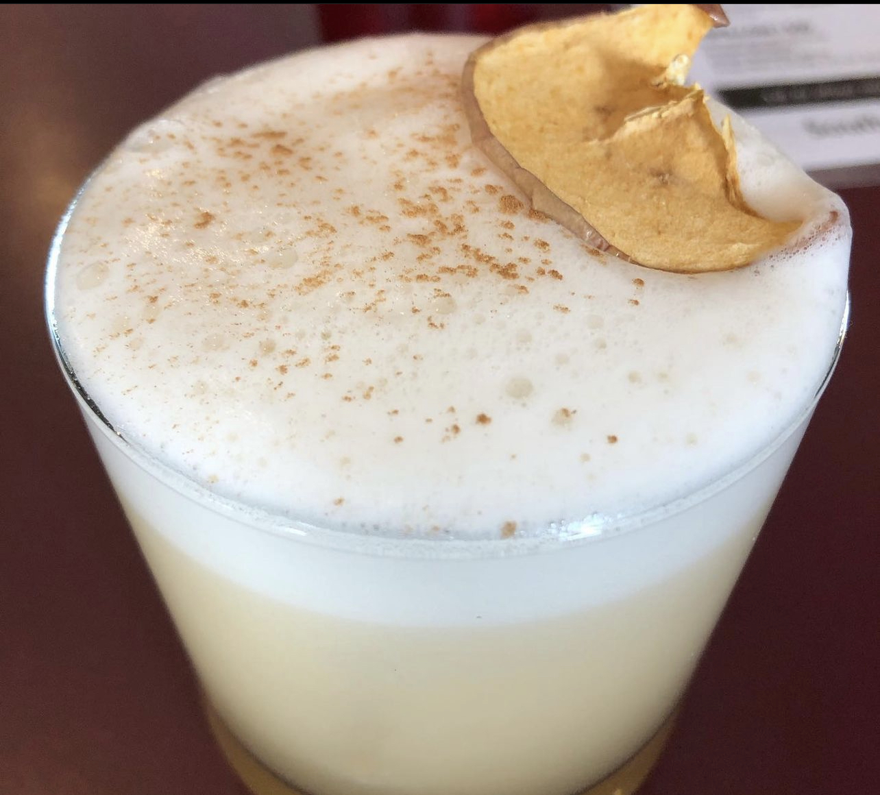 A frothy apple cinnamon sour topped with a dried apple chip