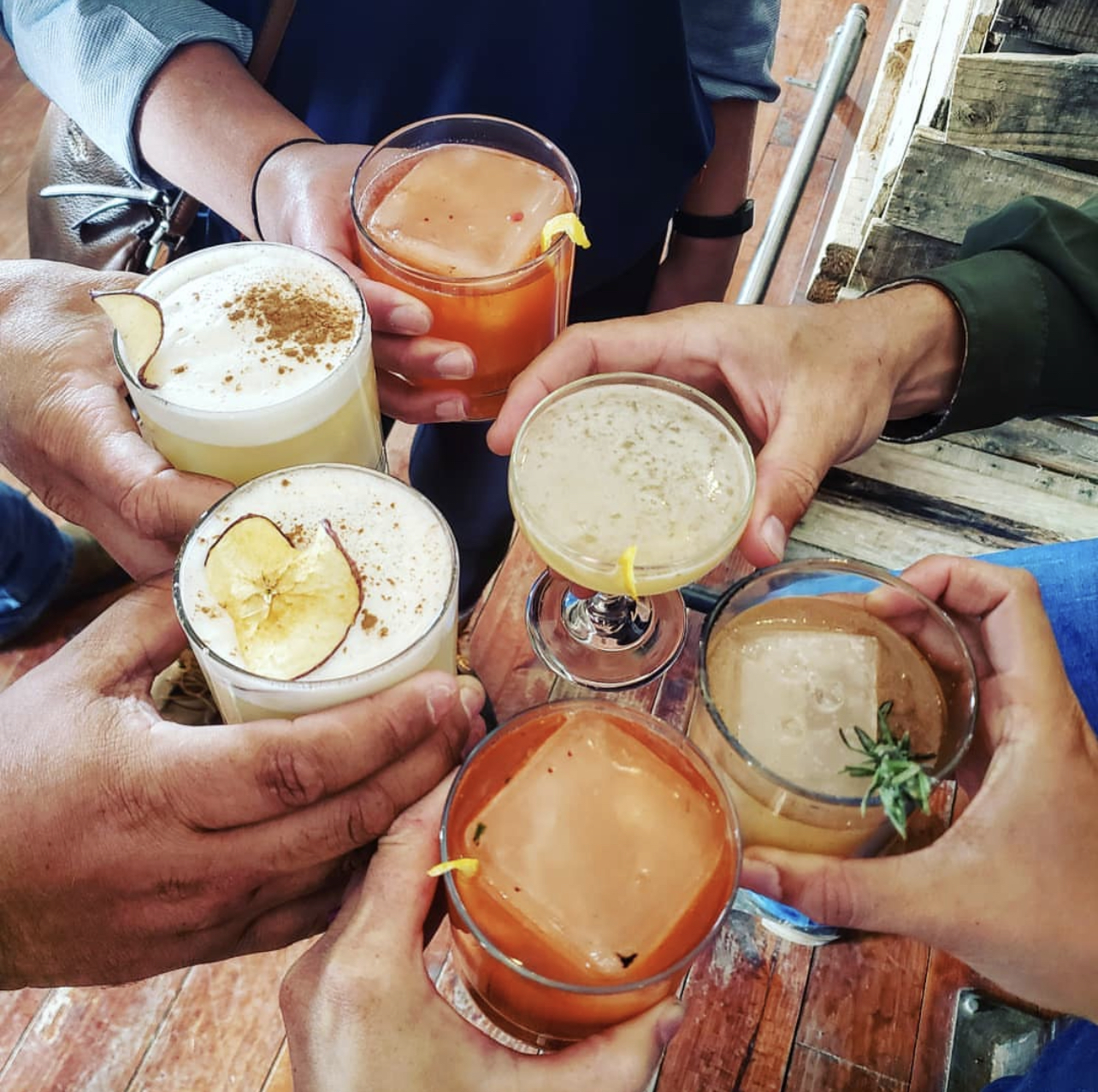 Friends toasting a round of seasonal cocktails over a wood table