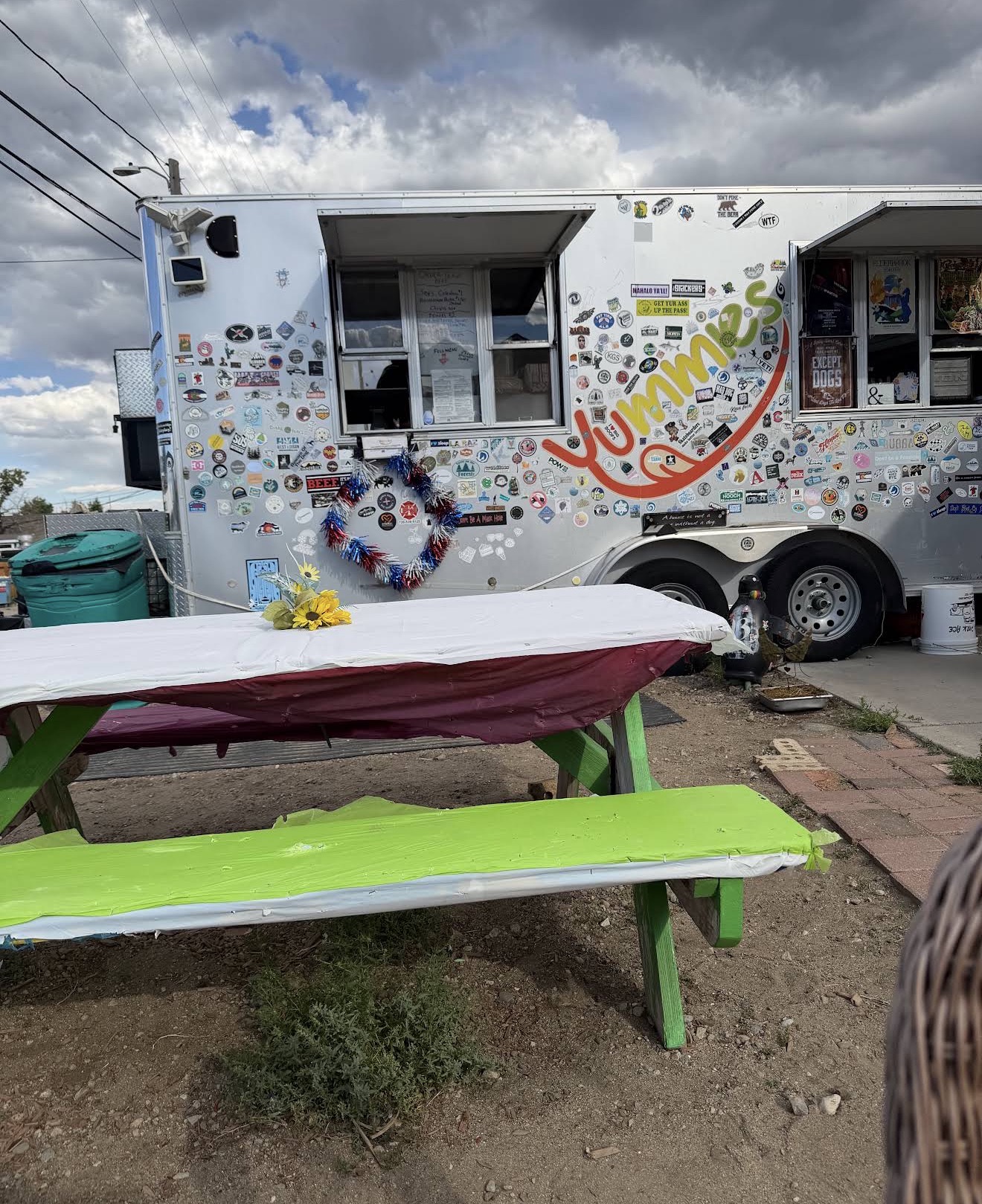 The sticker-covered Yummies food stand behind the distillery with a painted picnic table out front