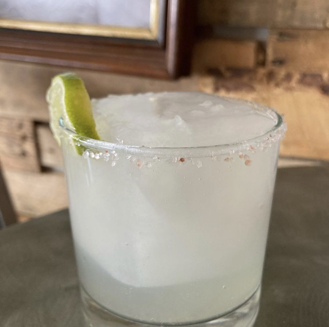 A salt-rimmed margarita with a lime wedge on the tasting room bar