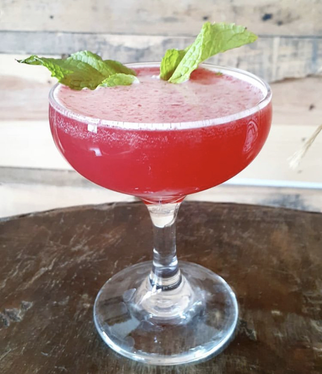 A strawberry-mint daiquiri in a coupe on a live-edge table