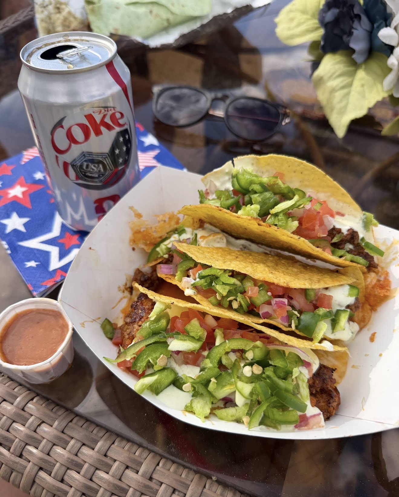 A loaded order of street tacos with pico, crema, and jalapeños on a patio table