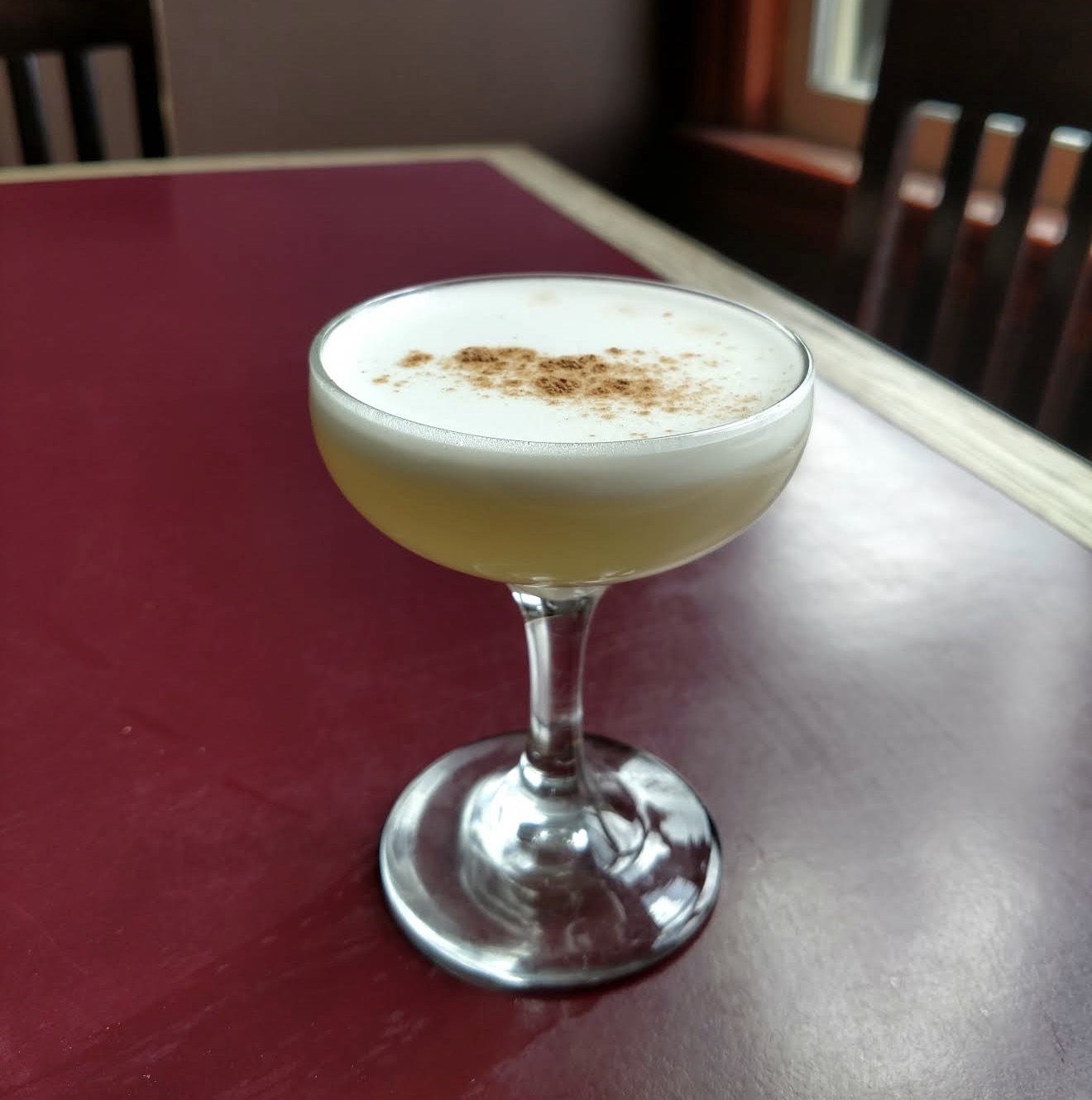 A cinnamon-dusted whiskey sour with a thick foam cap