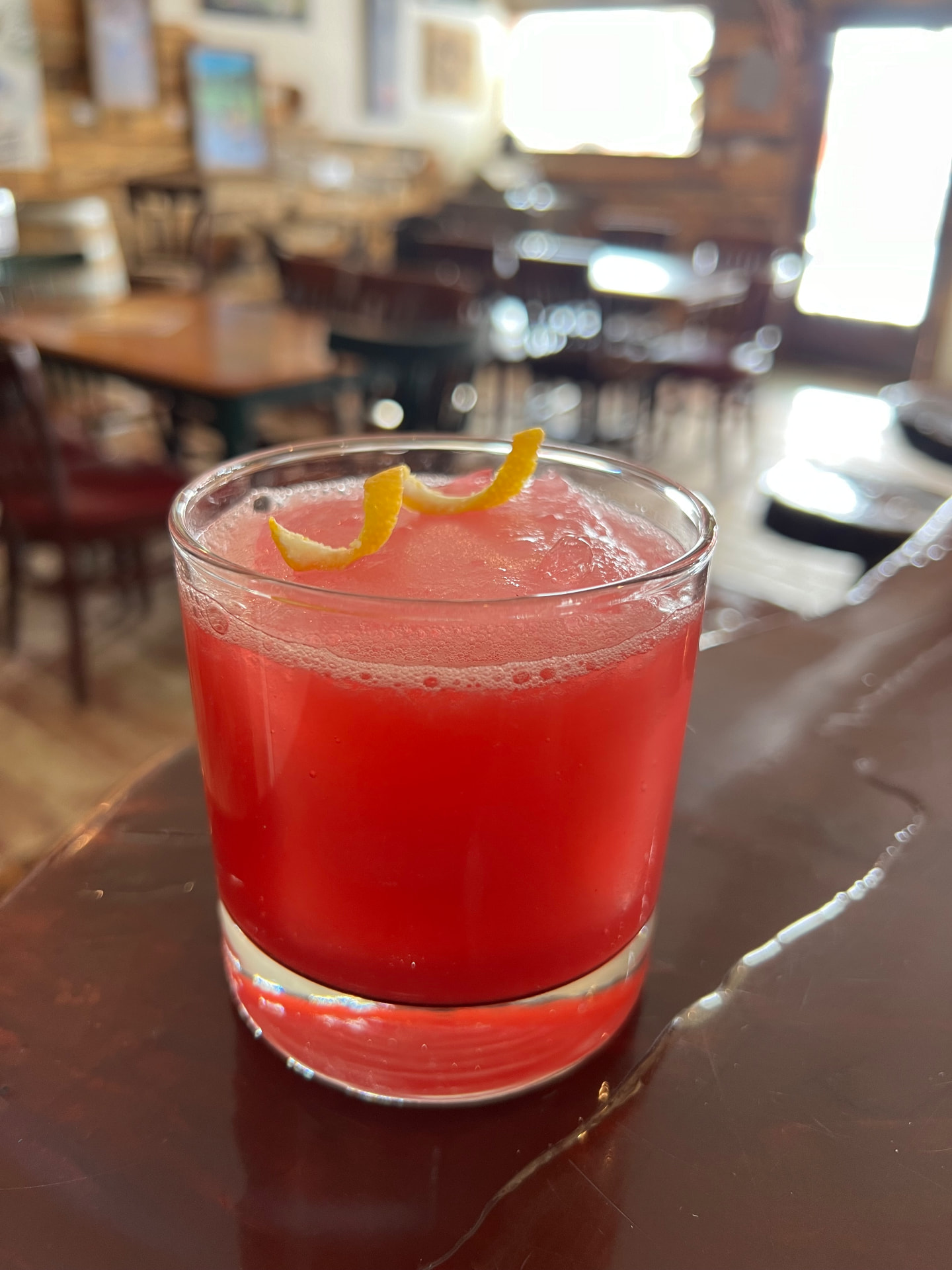 A bright red citrus cooler with a lemon twist on the tasting room bar