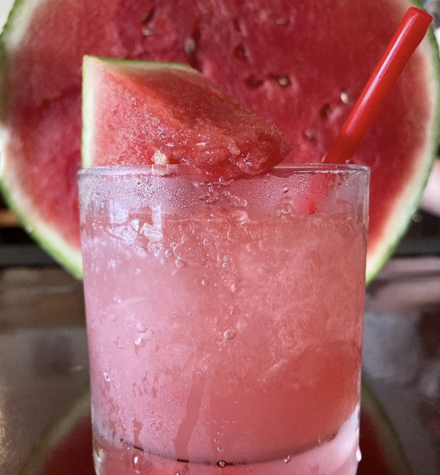 A watermelon cooler over crushed ice with a fresh melon wedge