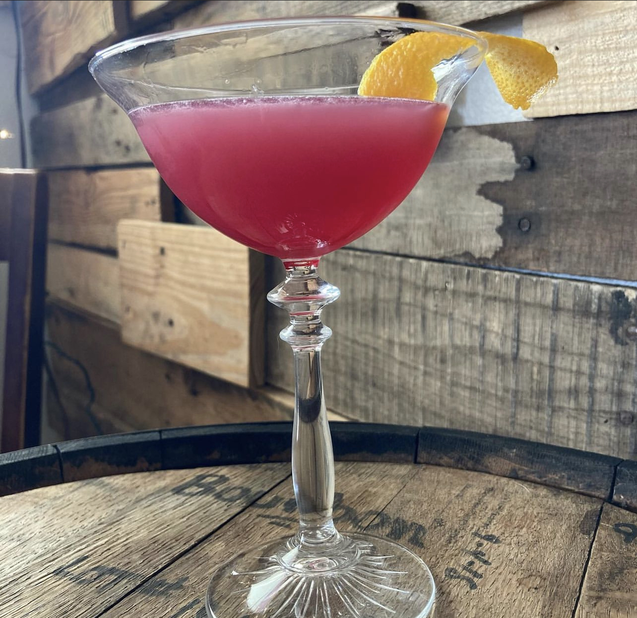 A ruby cosmo in a crystal coupe with an orange twist on a barrel top
