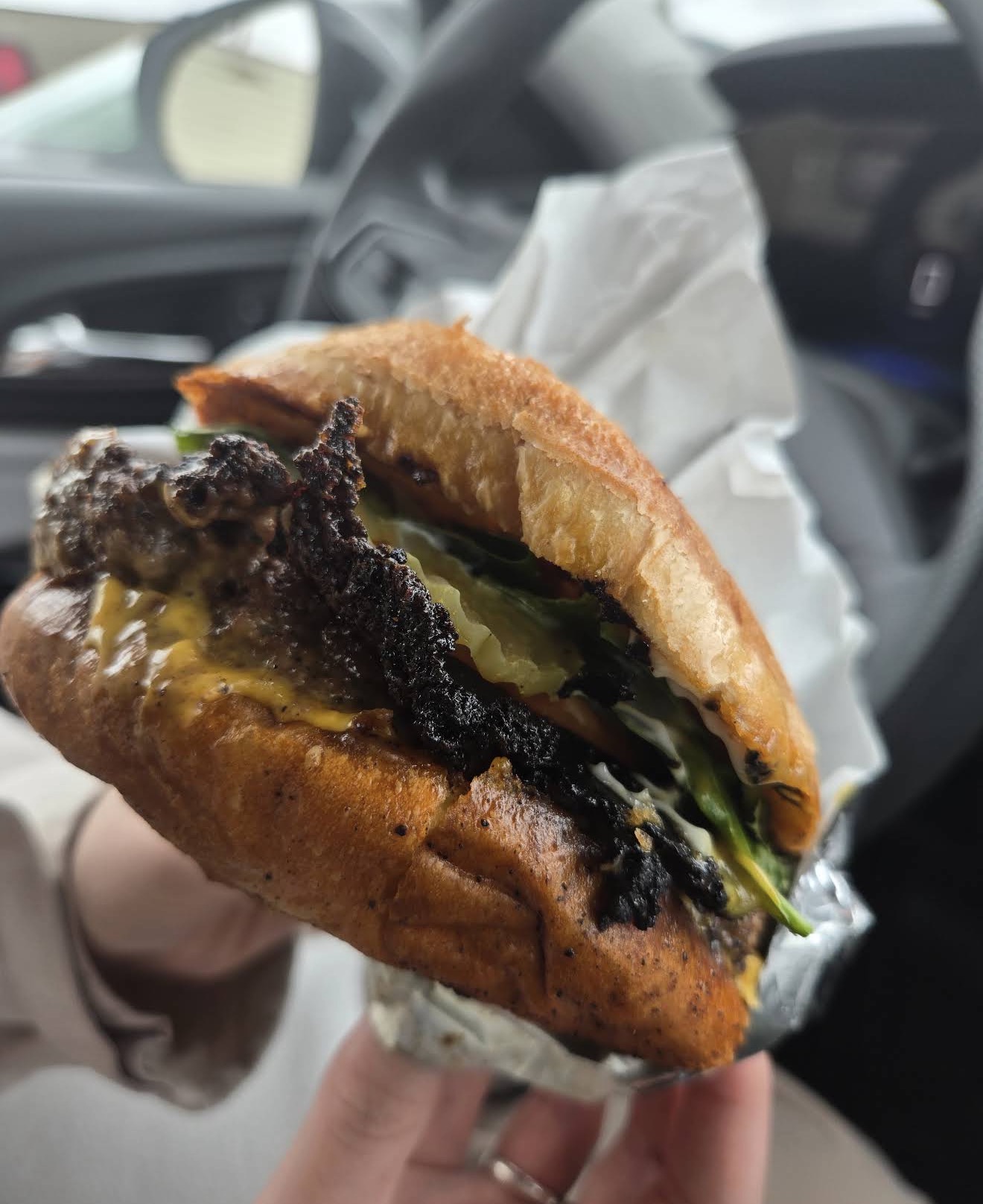 A cheeseburger with crispy bacon, lettuce, and pickles on a golden toasted bun