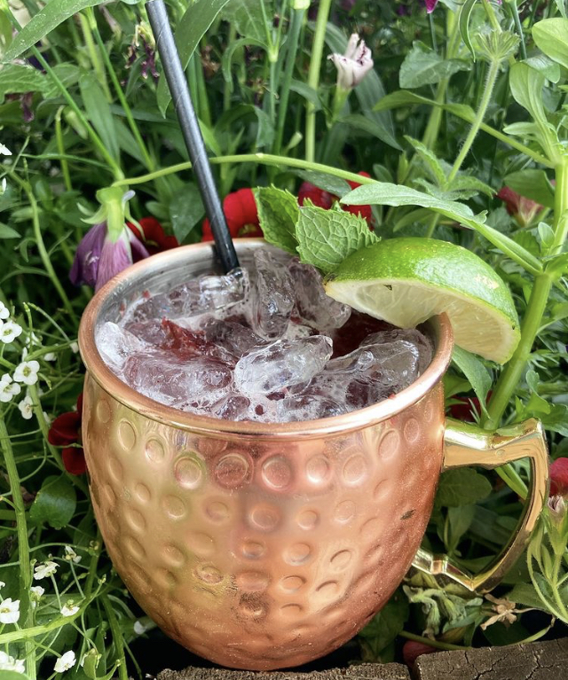 A copper mug mule with mint and lime nestled in summer flowers