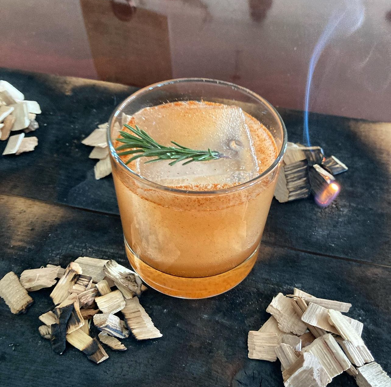 A smoked rosemary old fashioned with burning wood chips