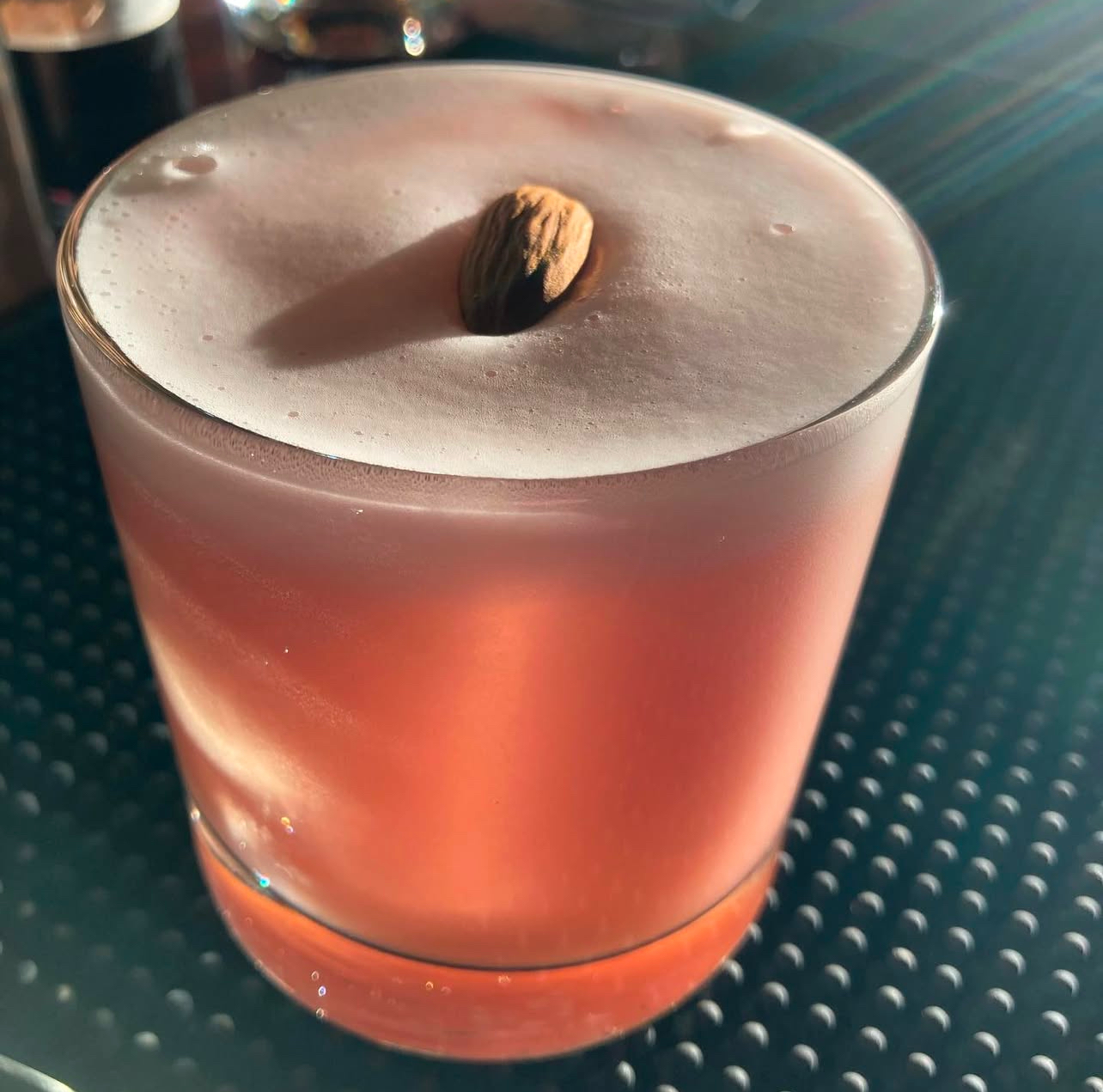 A silky almond whiskey sour crowned with foam and a single almond