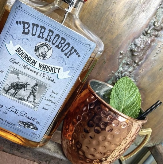 A copper mug mule with fresh mint beside the Burrobon Bourbon bottle