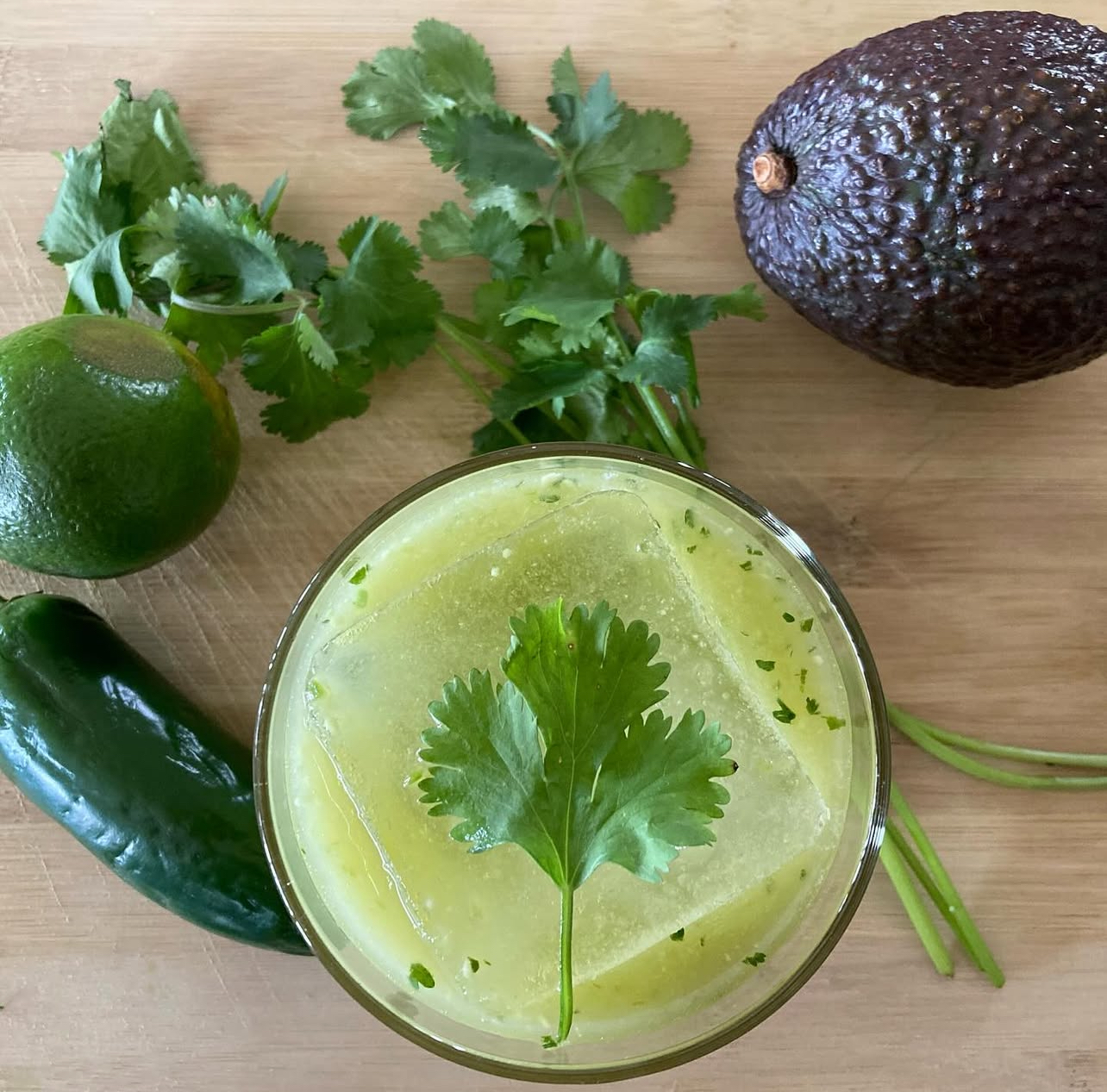 An overhead shot of a cilantro-lime cocktail with jalapeño, avocado and lime