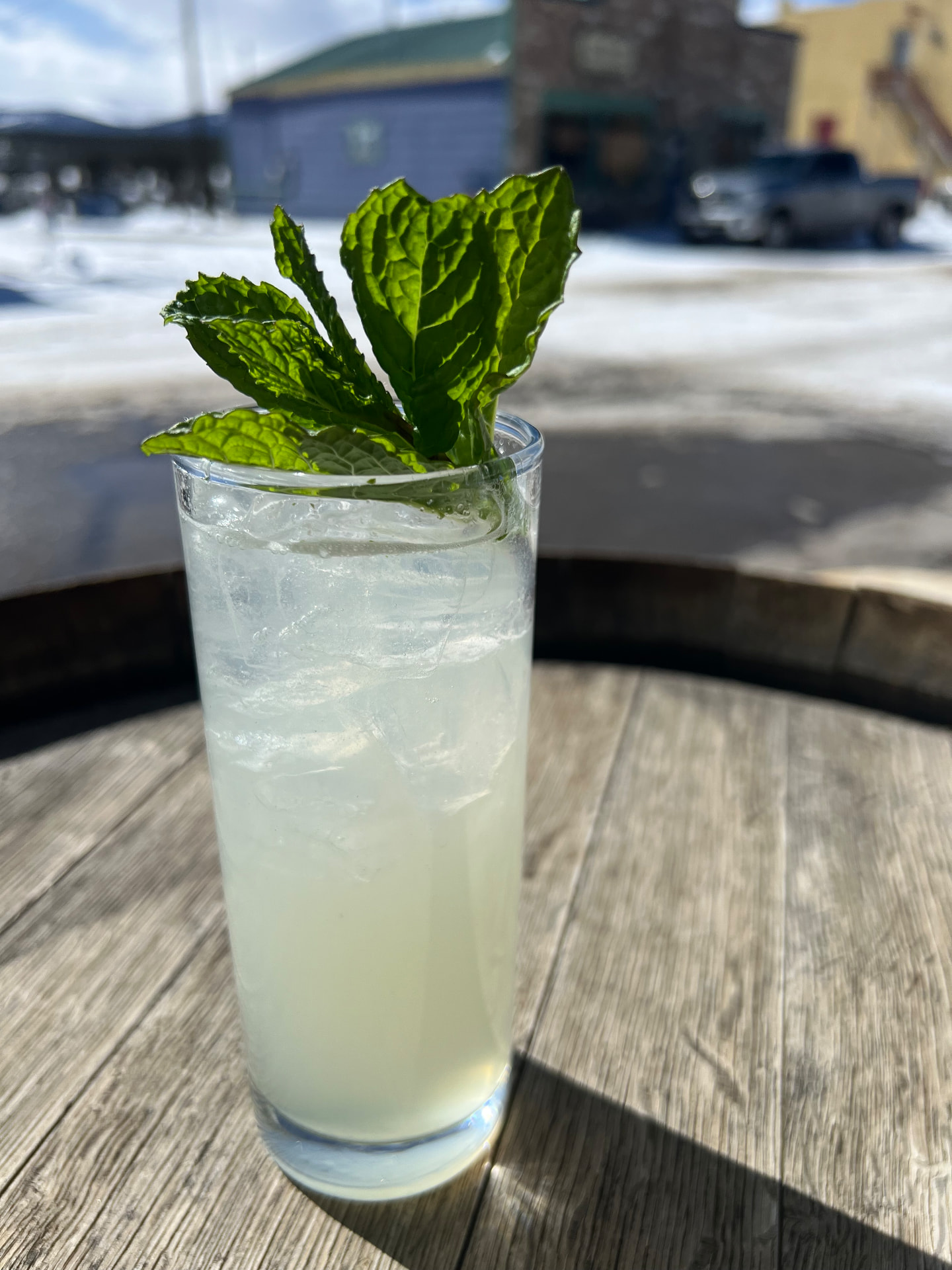 A tall mint mojito over ice on a barrel table in the winter sun