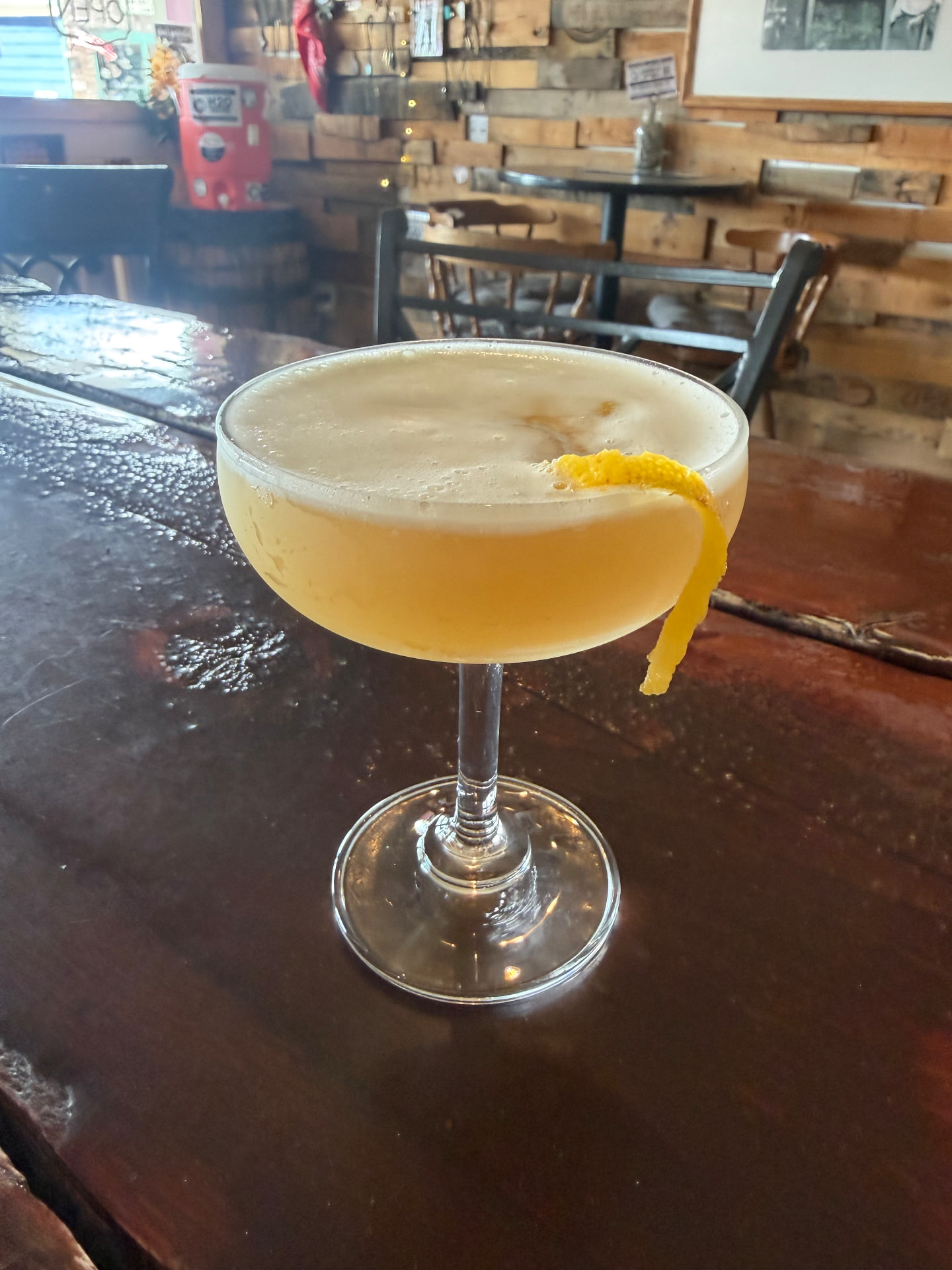 A frothy sidecar in a coupe with a long lemon twist on the tasting room bar