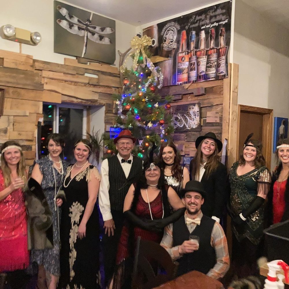 Guests dressed to the nines for the Prohibition Party beside the Christmas tree