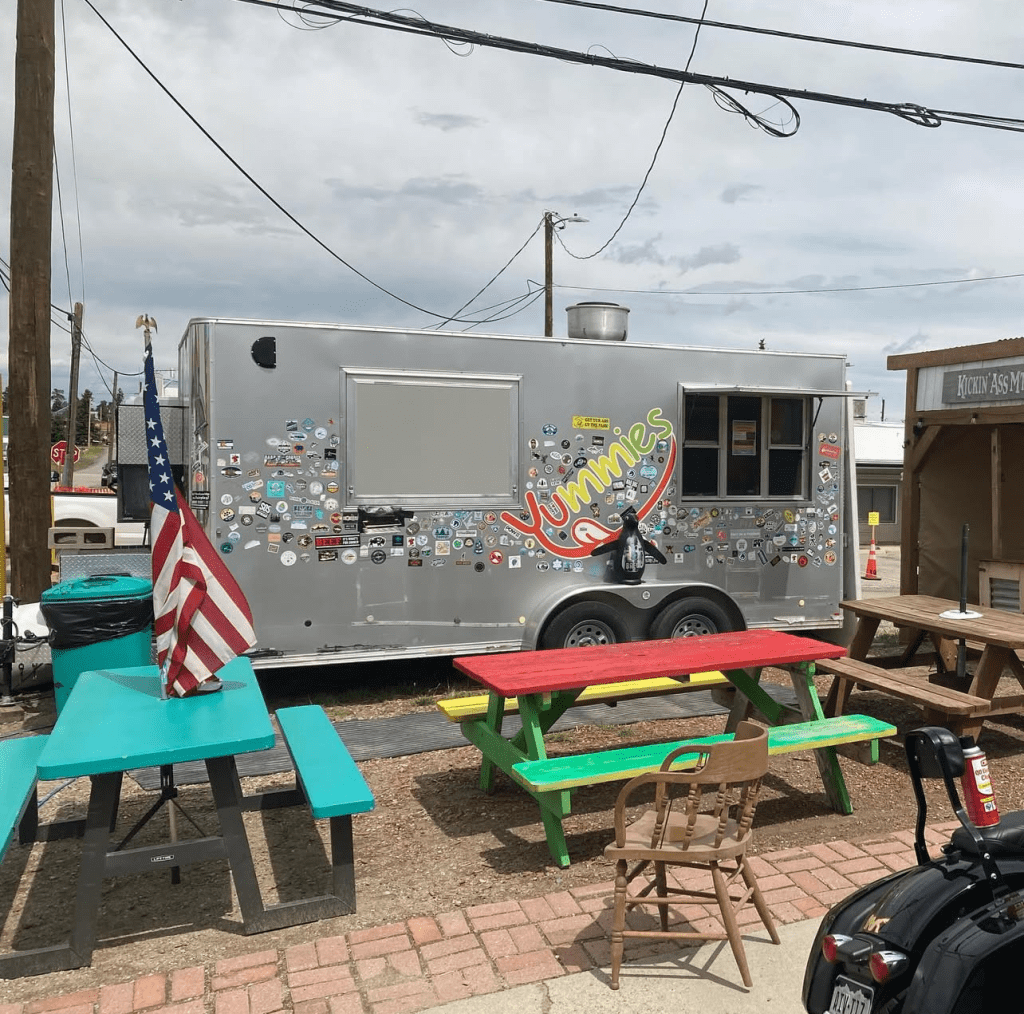 The Yummies food stand parked behind Snitching Lady Distillery with colorful picnic tables out front