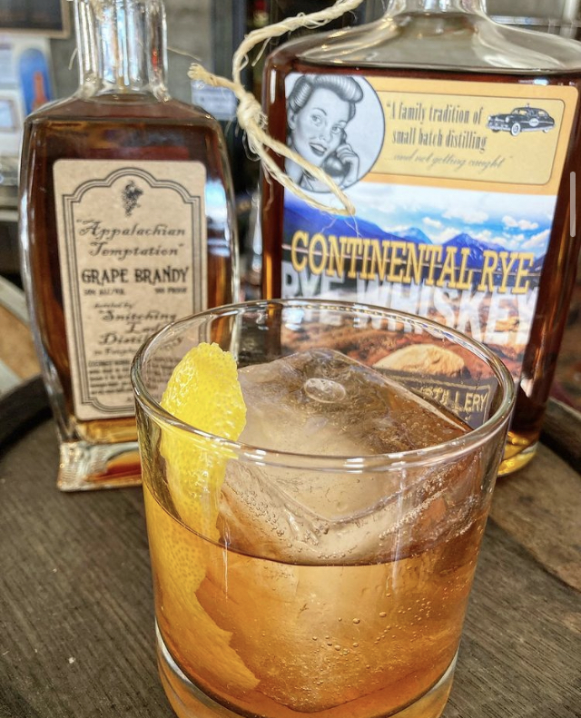 A Continental Rye old fashioned with the Grape Brandy bottle behind