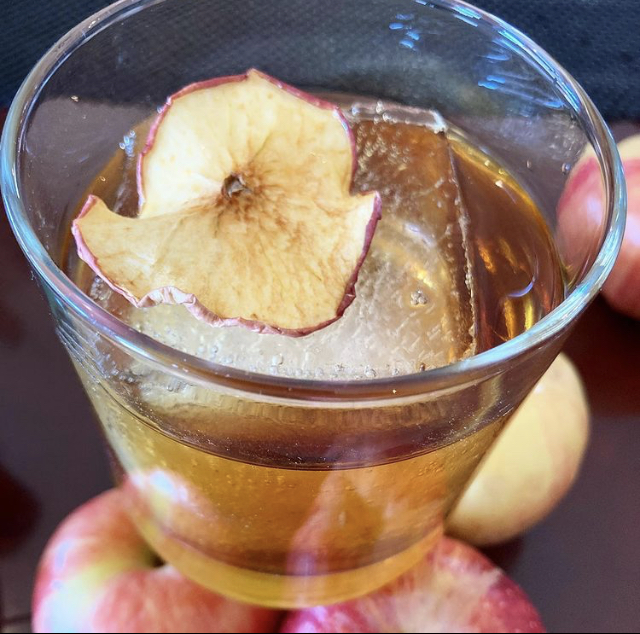 An apple cider cocktail garnished with a dried apple