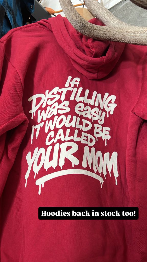 Maroon pullover hoodie with the 'If distilling was easy it would be called your mom' back print