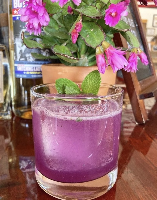 A bright purple cocktail with mint on the tasting-room bar
